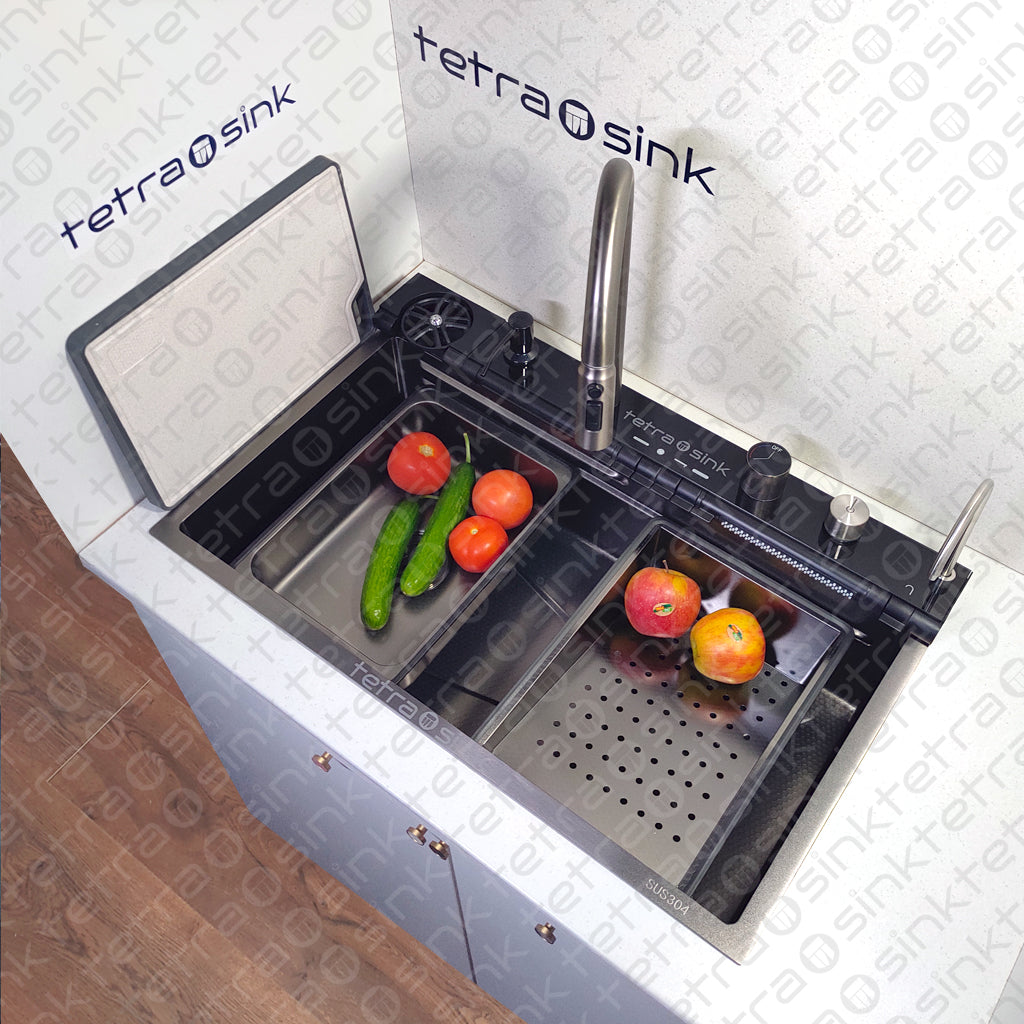 Multifunctional kitchen sink with deep trough and a waterfall mixer tap, featuring fresh vegetables in one of the bowls and the brand name 'Tetra Sink' visible.