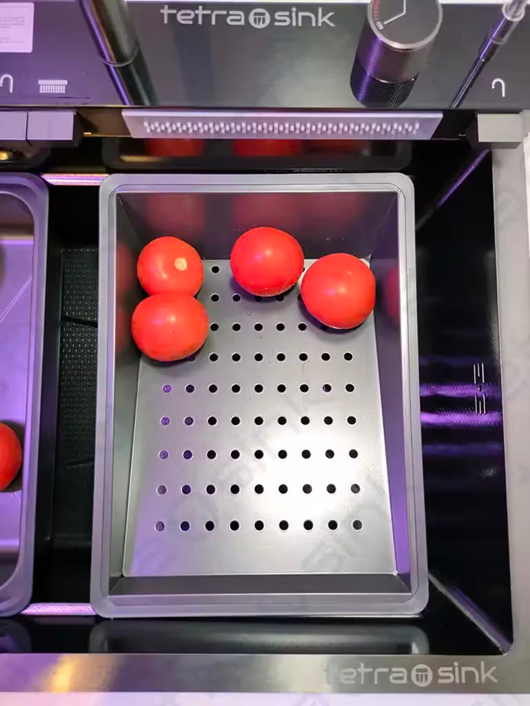Red tomatoes on a perforated metal tray inside a TetraSink Multifunctional sink best Modern kitchen sink.