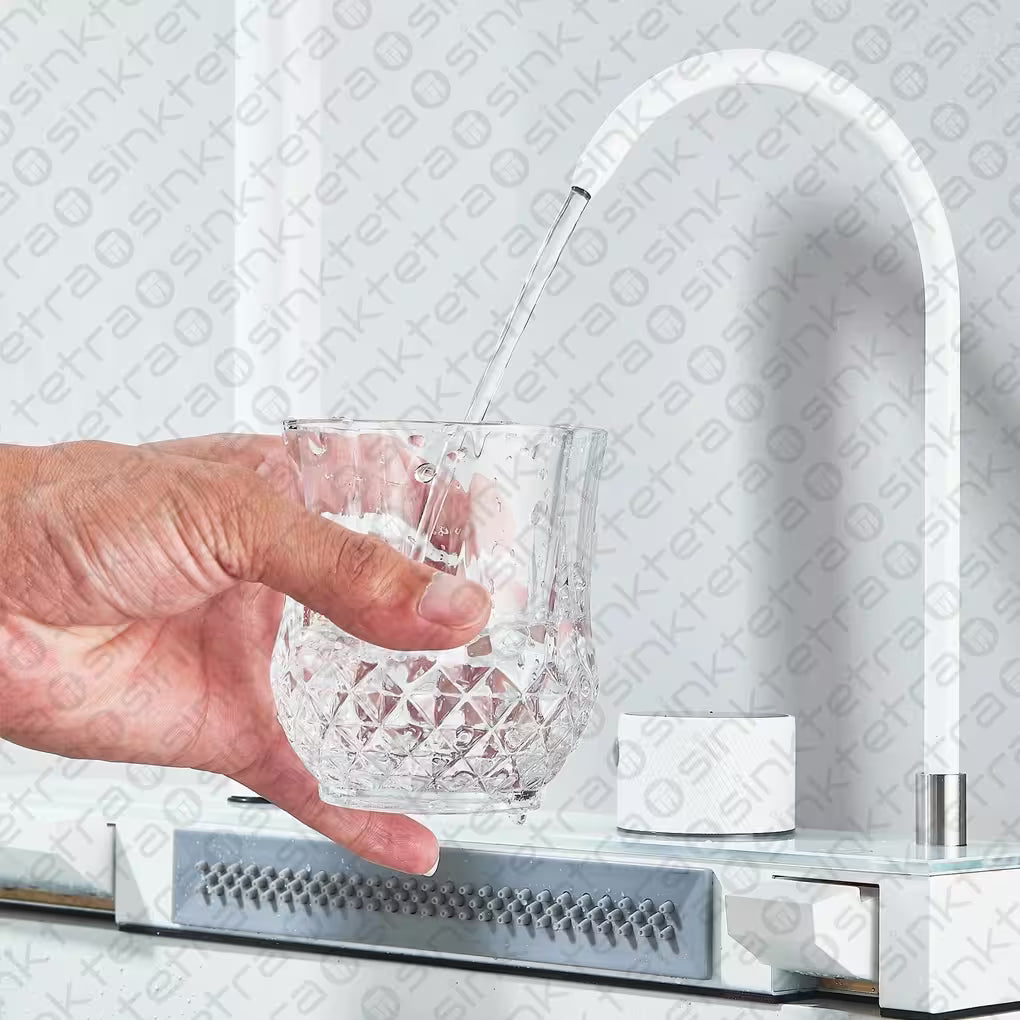 Hand filling a glass with water from a modern tetrasink kitchen faucet.